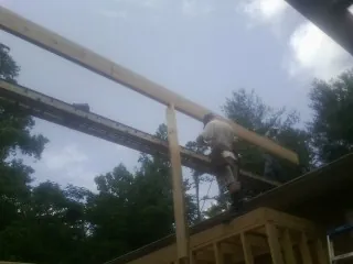Carpenter setting a ridge beam over a new addition frame — Ice Dam Removal by Roofing Brothers in Pleasant Plain