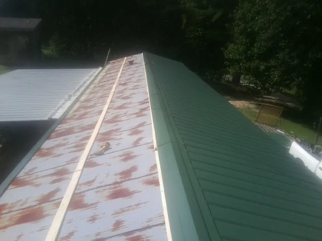 Old rusted panels beside newly installed green metal roofing — Wind Damage Roof Repair by Roofing Brothers in Pleasant Plain