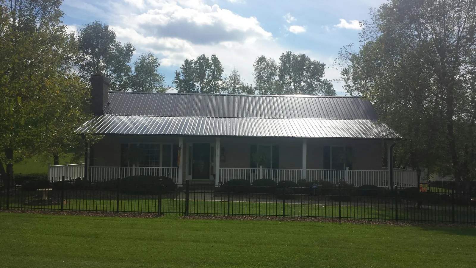 Gray metal roof on a brick ranch with a full width front porch — Gutter Guard Installation work by our crew in Pleasant Plain