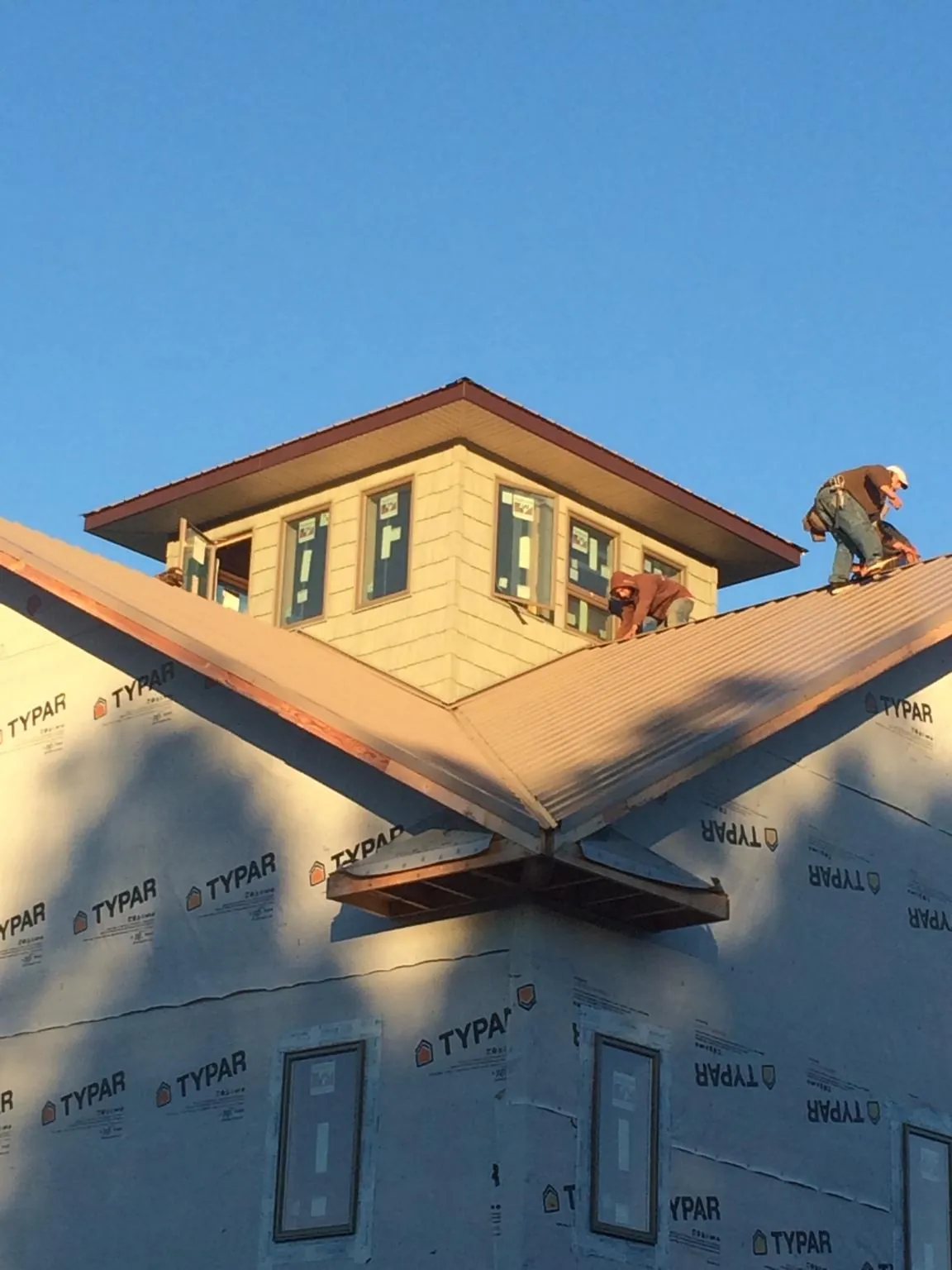 Roofers working around a rooftop cupola on a new metal roof at sunset — Roof Waterproofing in Pleasant Plain by Roofing Brothers